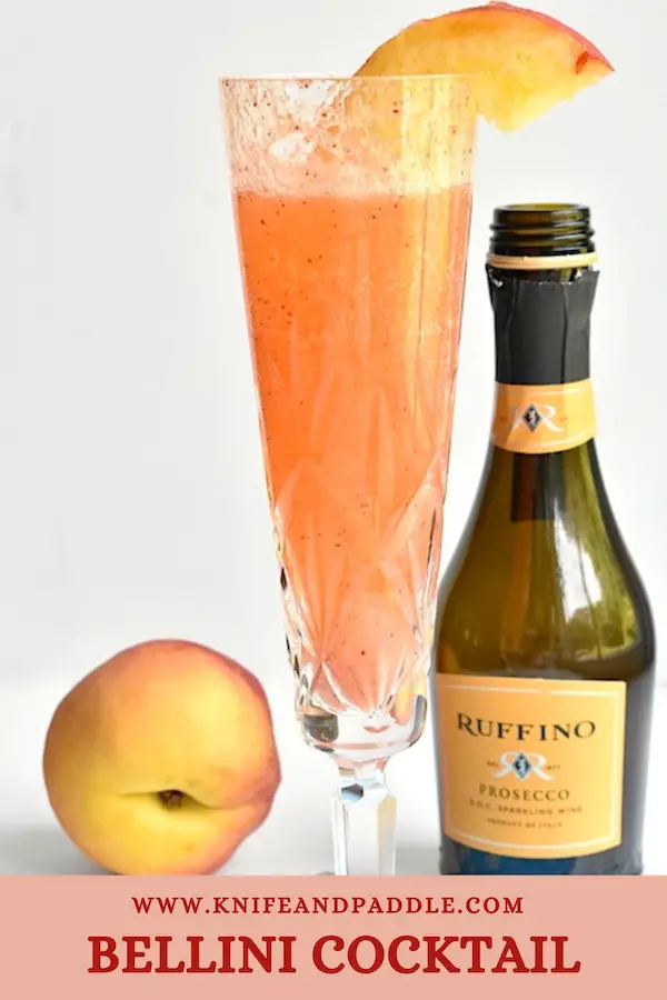 Refreshing Bellini Cocktail with a peach wedge in a Champagne glass