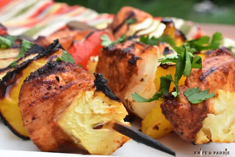 BBQ recipe with pineapple, onions and peppers on skewers topped with fresh cilantro