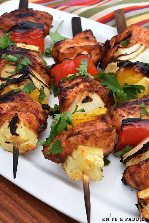 BBQ recipe with pineapple, onions and peppers on skewers topped with fresh cilantro