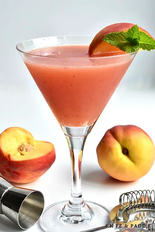 Peach martini with a peach wedge and a mint sprig