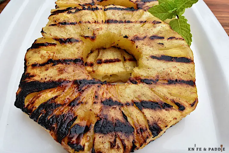 Grilled tropical fruit on a plate with a mint sprig