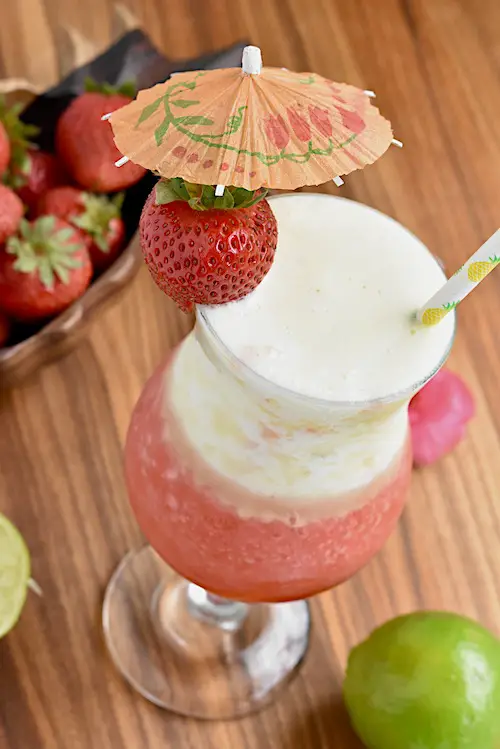 The Miami Vice Cocktail in a hurricane glass garnished with a fresh strawberry and a cocktail umbrella