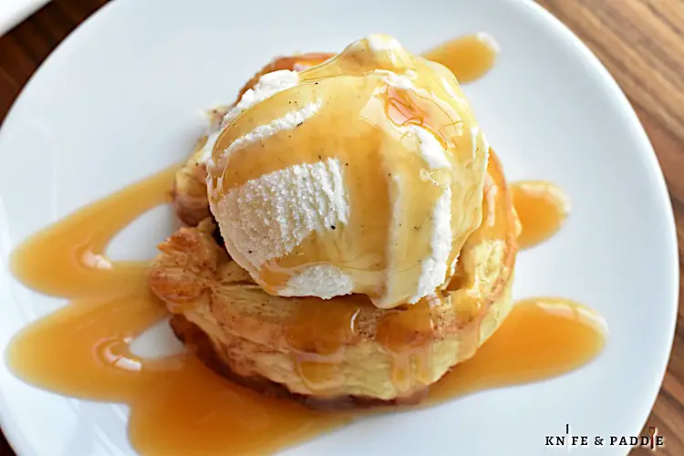 Apple Pinwheels topped with vanilla ice cream and caramel sauce on a plate