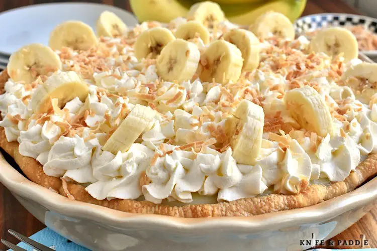 Classic Banana Cream Pie topped with homemade whipped cream, fresh bananas and toasted coconut