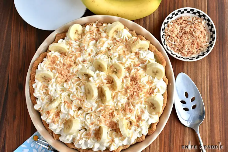 Classic Banana Cream Pie topped with homemade whipped cream, fresh bananas and toasted coconut