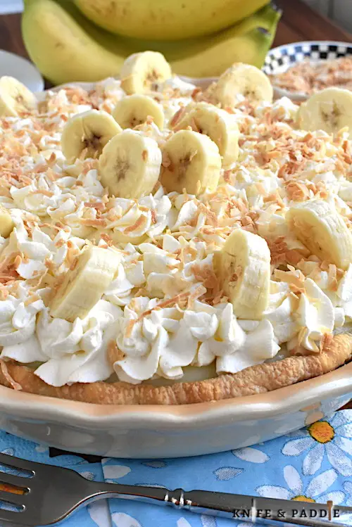 Classic Banana Cream Pie topped with homemade whipped cream, fresh bananas and toasted coconut