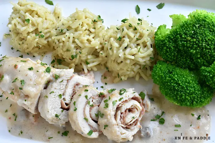 Crockpot Chicken Saltimbocca served on a plate topped with fresh parsley and accompanied by rice and broccoli