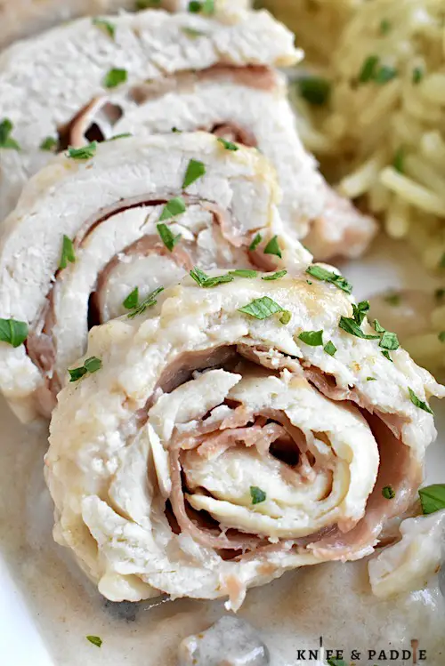 Crockpot Chicken Saltimbocca served on a plate topped with fresh parsley and accompanied by rice and broccoli