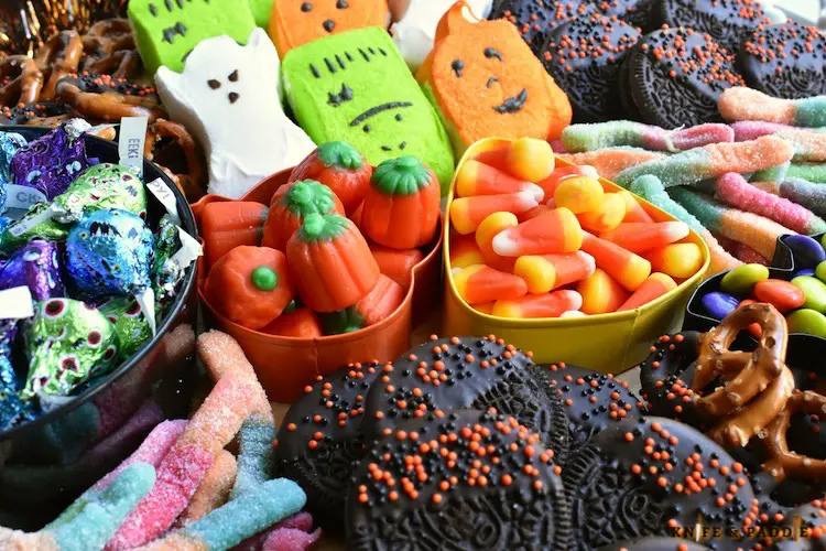 Halloween Charcuterie Board filled with Ghost, Frankenstein and Pumpkin Pepps, Pretzels, Candy Corn, Pumpkin Candy Corn, Gummy worms, M&M's, Oreos, Hershey's Kisses arranged on a platter