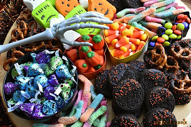 Halloween Charcuterie Board filled with Ghost, Frankenstein and Pumpkin Pepps, Pretzels, Candy Corn, Pumpkin Candy Corn, Gummy worms, M&M's, Oreos, Hershey's Kisses arranged on a platter