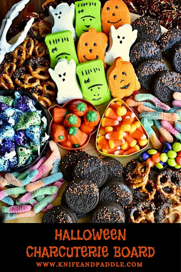 Halloween Charcuterie Board filled with Ghost, Frankenstein and Pumpkin Pepps, Pretzels, Candy Corn, Pumpkin Candy Corn, Gummy worms, M&M's, Oreos, Hershey's Kisses arranged on a platter