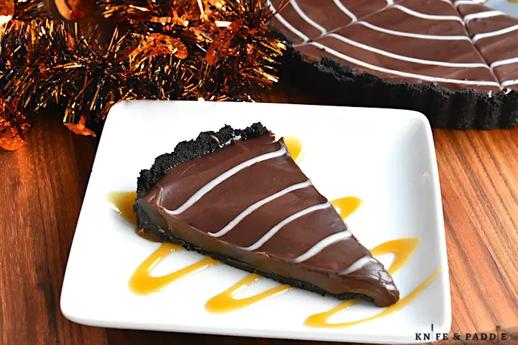 Slice of cookie pie with an Oreo crust, gooey inside, chocolate ganache and drizzle