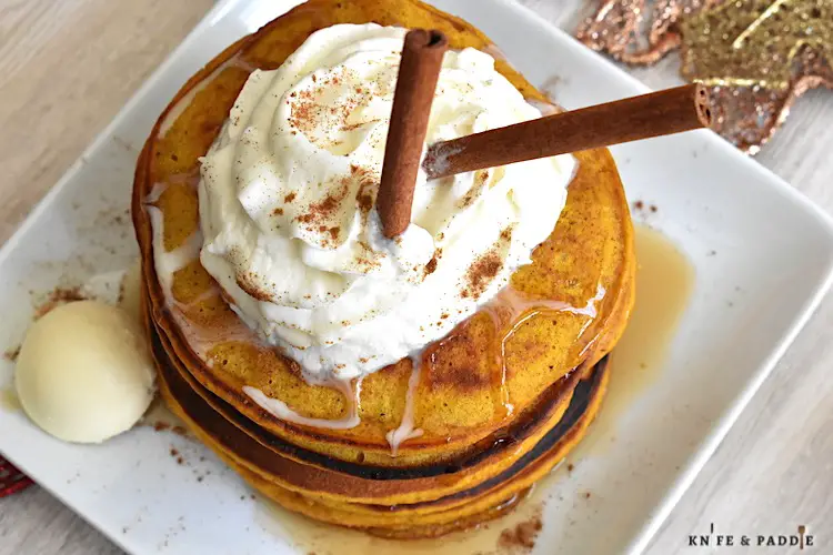 Pumpkin Pancakes with maple syrup topped with whipped cream