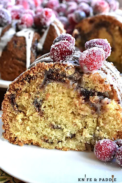 Slice of Cranberry Bundt Cake with a glaze drizzle and sugared cranberries