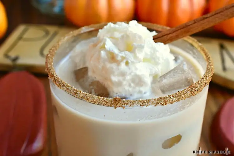 Pumpkin Spice White Russian with spiced rim and topped with whipped cream and a cinnamon stick